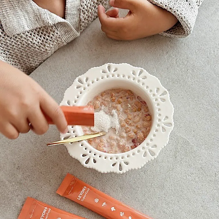 子どもがお粥に粉をかける手元